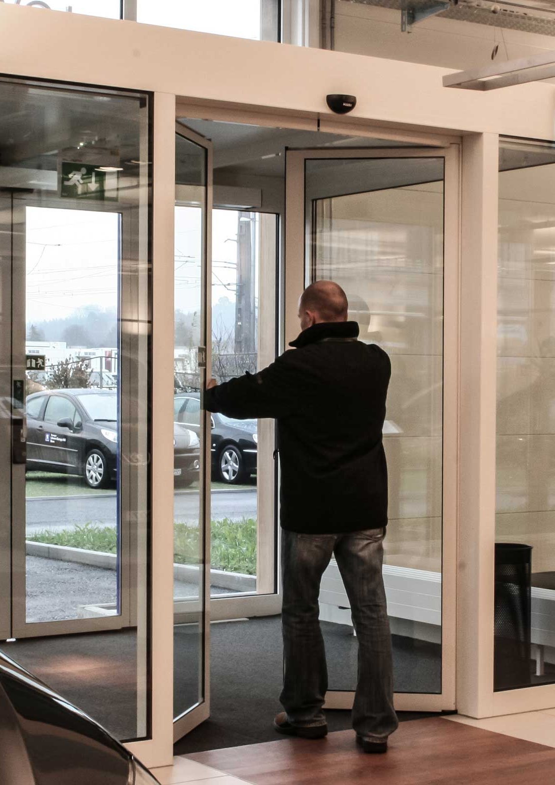 Eine Person, die im Autohaus die Türflügeln einer automatischen Fluchtweg-Schiebetüre öffnet